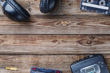 Image showing Cassette tapes, cassette player and headphones over wooden table. top view.