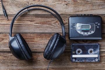 Image showing Headphones, player and retro compact cassette over wooden background. Top view