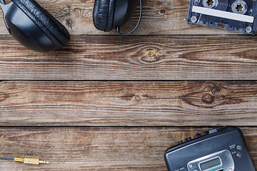 Image showing Cassette tapes, cassette player and headphones over wooden table. top view.