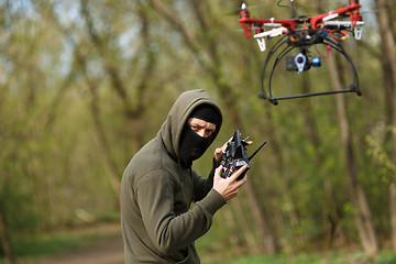 Image showing Man in mask operating a drone with remote control.