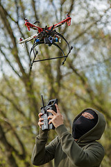 Image showing Man in mask operating a drone with remote control.