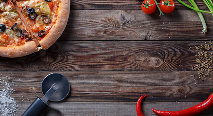 Image showing Tasty pizza with ingridients on a wooden board.