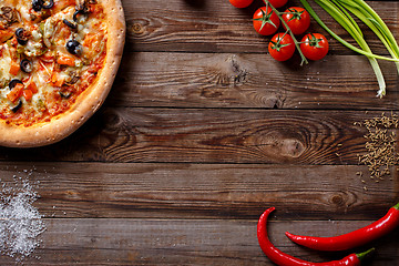 Image showing Italian pizza with tomatoes on a wooden table, top view.