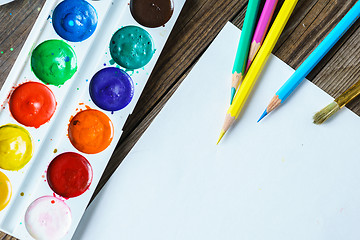 Image showing Art tools. Watercolor Paints and brushes with blank white paper  on wooden background close up.