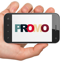 Image showing Marketing concept: Hand Holding Smartphone with Promo on  display