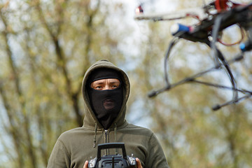 Image showing Man in mask operating a drone with remote control.