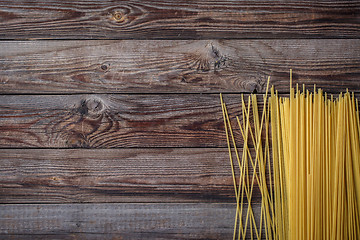 Image showing Yellow long spaghetti on black background. Raw spaghetti.