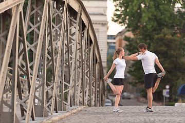 Image showing couple warming up and stretching before jogging