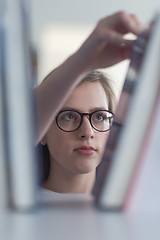 Image showing portrait of famale student selecting book to read in library