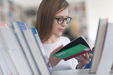 Image showing portrait of famale student selecting book to read in library