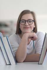 Image showing portrait of famale student selecting book to read in library