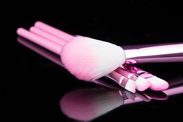 Image showing lipstick with a brush make-up on black 