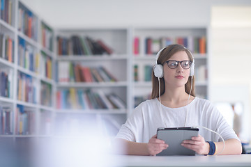 Image showing female student study in library, using tablet and searching for 