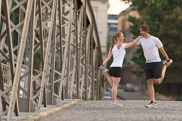 Image showing couple warming up and stretching before jogging