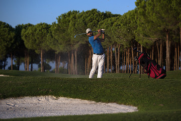 Image showing golfer hitting a sand bunker shot on sunset