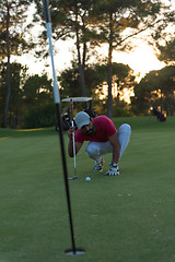 Image showing golf player aiming perfect  shot on beautiful sunset