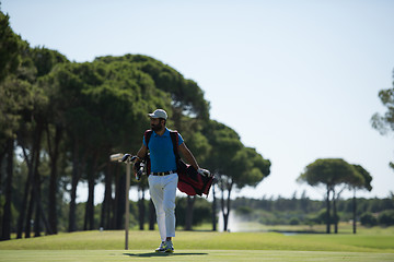 Image showing golf player walking and carrying bag