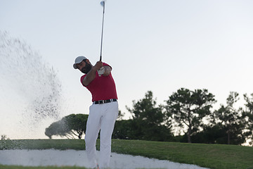 Image showing golfer hitting a sand bunker shot on sunset