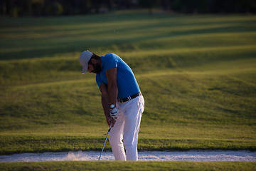 Image showing golfer hitting a sand bunker shot on sunset