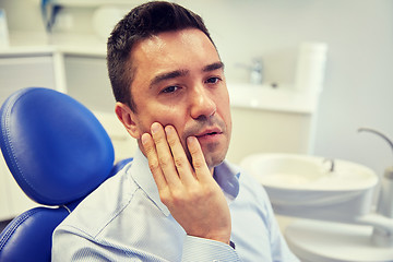 Image showing man having toothache and sitting on dental chair