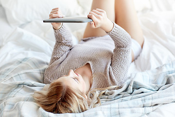 Image showing happy young woman with tablet pc in bed at home