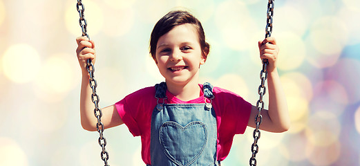 Image showing happy little girl swinging on swing over lights