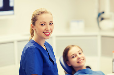 Image showing happy female dentist with patient girl at clinic