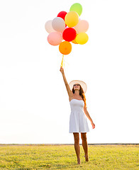 Image showing smiling young woman in sunglasses with balloons