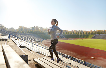 Image showing happy young woman running upstairs on stadium