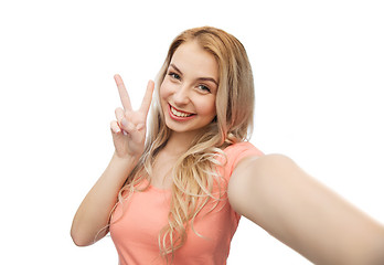 Image showing smiling woman taking selfie and showing peace sign