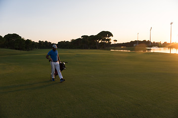 Image showing golfer  walking and carrying golf  bag at beautiful sunset