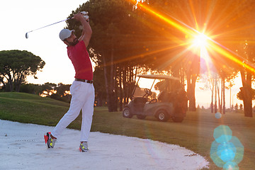 Image showing golfer hitting a sand bunker shot on sunset