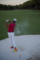 Image showing golfer hitting a sand bunker shot on sunset