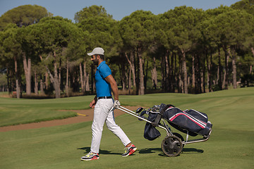 Image showing golf player walking with wheel bag