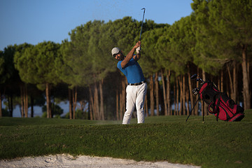 Image showing golfer hitting a sand bunker shot on sunset