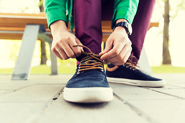 Image showing close up of male hands tying shoe laces on street