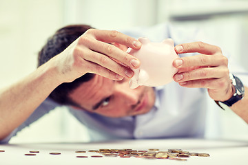 Image showing businessman with piggy bank and coins at office