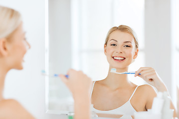 Image showing woman with toothbrush cleaning teeth at bathroom