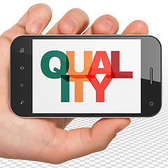 Image showing Advertising concept: Hand Holding Smartphone with Quality on  display