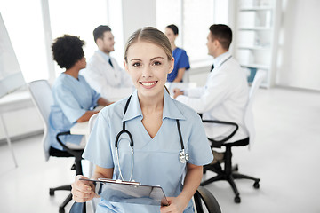 Image showing happy doctor with clipboard over group of medics