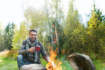 Image showing happy man drinking hot tea near camp fire