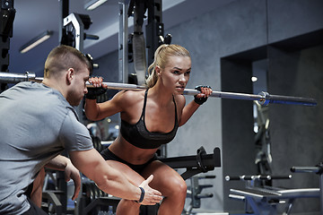 Image showing man and woman with bar flexing muscles in gym