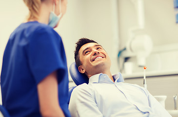 Image showing female dentist with happy male patient at clinic