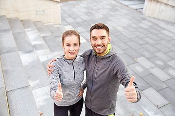 Image showing smiling couple showing thumbs up on city street