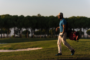 Image showing golfer  walking and carrying golf  bag at beautiful sunset