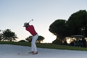 Image showing golfer hitting a sand bunker shot on sunset