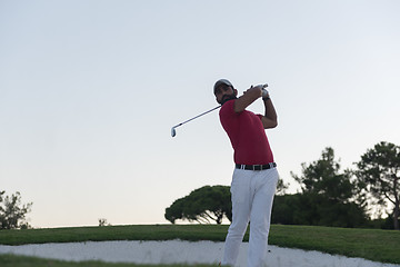 Image showing golfer hitting a sand bunker shot on sunset