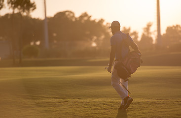 Image showing golfer  walking and carrying golf  bag at beautiful sunset