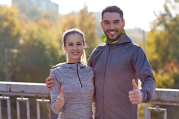 Image showing smiling couple showing thumbs up outdoors