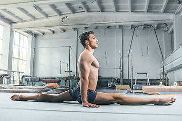 Image showing caucasian man gymnastic acrobatics equilibrium posture at gym background